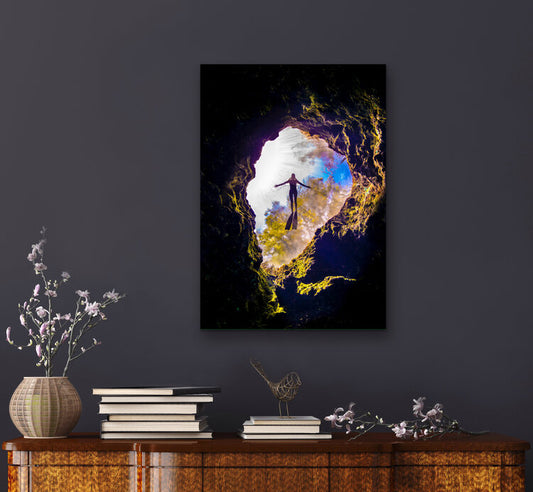 Underwater view looking up through a moss-rimmed spring cavern opening as a freediver floats silhouetted against sunlit water and spring foliage above.